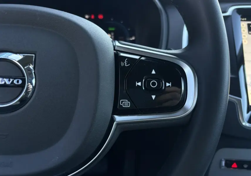 Gros plan sur le côté droit du volant noir du Volvo XC90 2024 avec commandes vocales et multimédia intégrées.