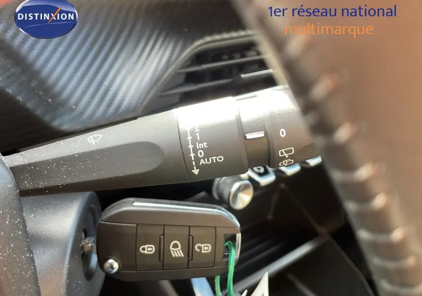 Gros plan sur la commande d'essuie-glace et la clé insérée dans le contacteur d'une Peugeot 2008 bleu Vertigo 2024.