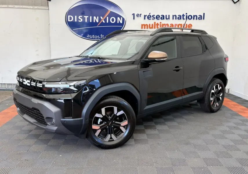 Dacia Duster noir en 3/4 avant droit, avec jantes bicolores et rétroviseurs couleur bronze, sur fond intérieur showroom.