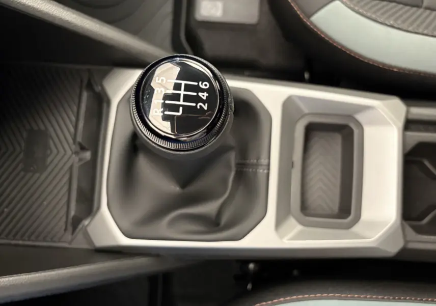 Le levier de vitesses manuel noir du Dacia Duster 2025 en vue plongeante, entouré de la console centrale grise.