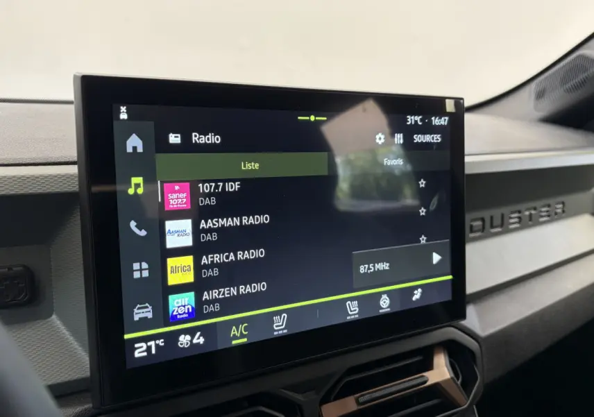 Écran tactile central affichant la radio dans l'habitacle du Dacia Duster noir, tableau de bord avec logo Duster visible