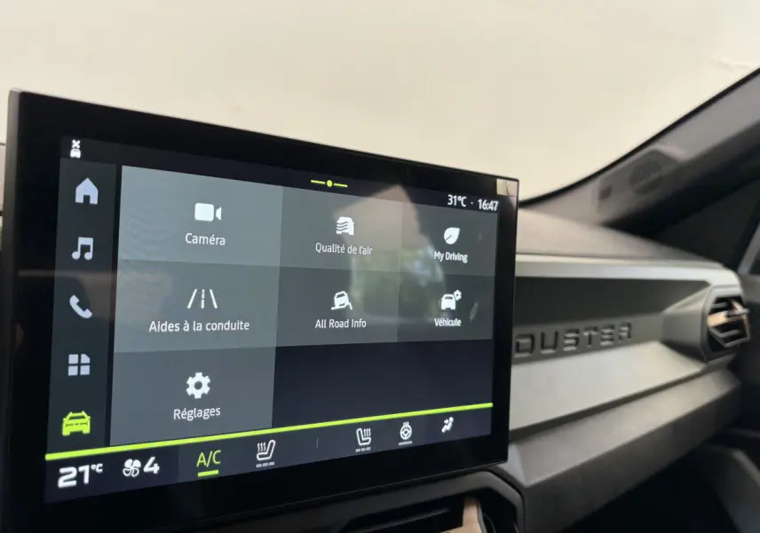 Écran tactile central affichant les aides à la conduite dans l'habitacle noir du Dacia Duster 2025 côté passager.
