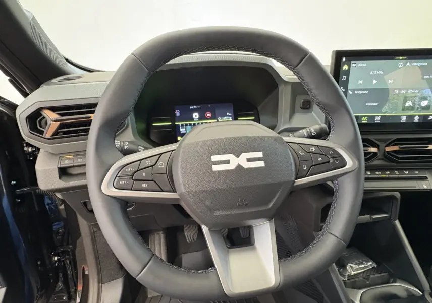 Vue intérieure centrée sur le volant cuir du Dacia Duster 2025 noir avec tableau de bord numérique et écran tactile.