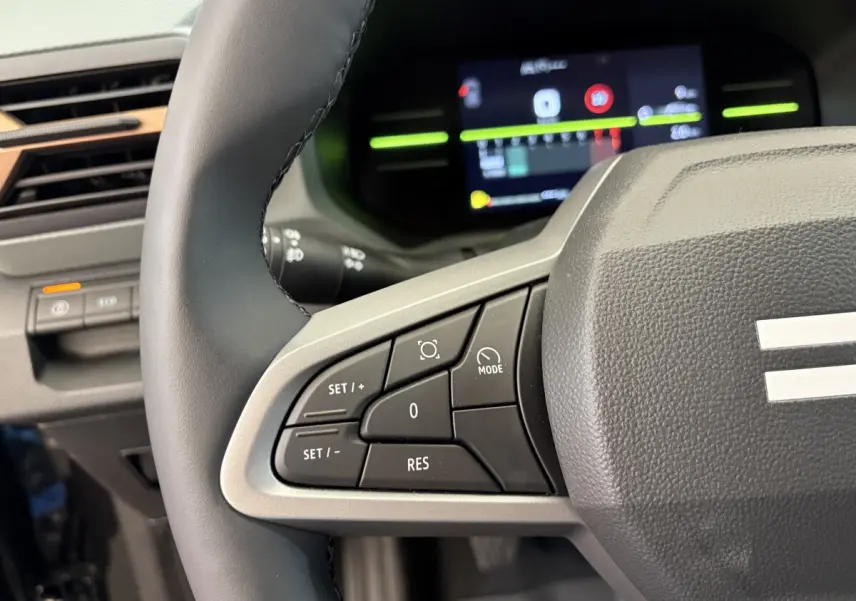 Gros plan sur le côté gauche du volant cuir du Dacia Duster 2025 avec commandes multifonctions et tableau de bord numérique.