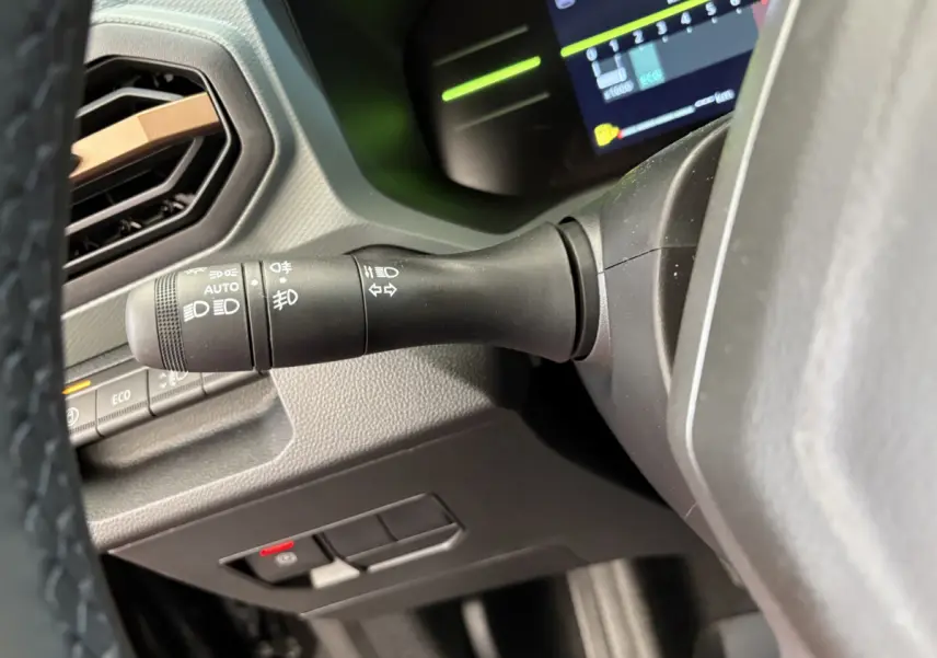 Gros plan sur la manette de phares et clignotants du tableau de bord du Dacia Duster noir 2025, version hybride.