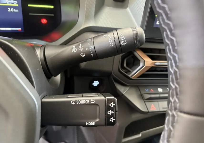 Gros plan sur la commande multifonction et le commodo d’essuie-glace du tableau de bord du Dacia Duster noir 2025.
