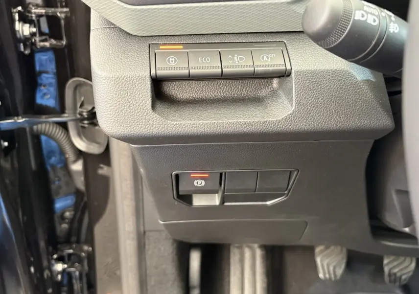 Vue rapprochée des commandes côté gauche du tableau de bord du Dacia Duster noir, avec boutons ECO et frein à main électrique.
