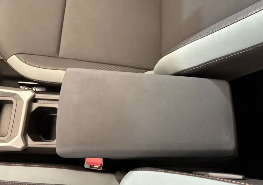 Accoudoir central noir et sièges bicolores gris et noir du Dacia Duster 2025 vue de dessus côté intérieur.