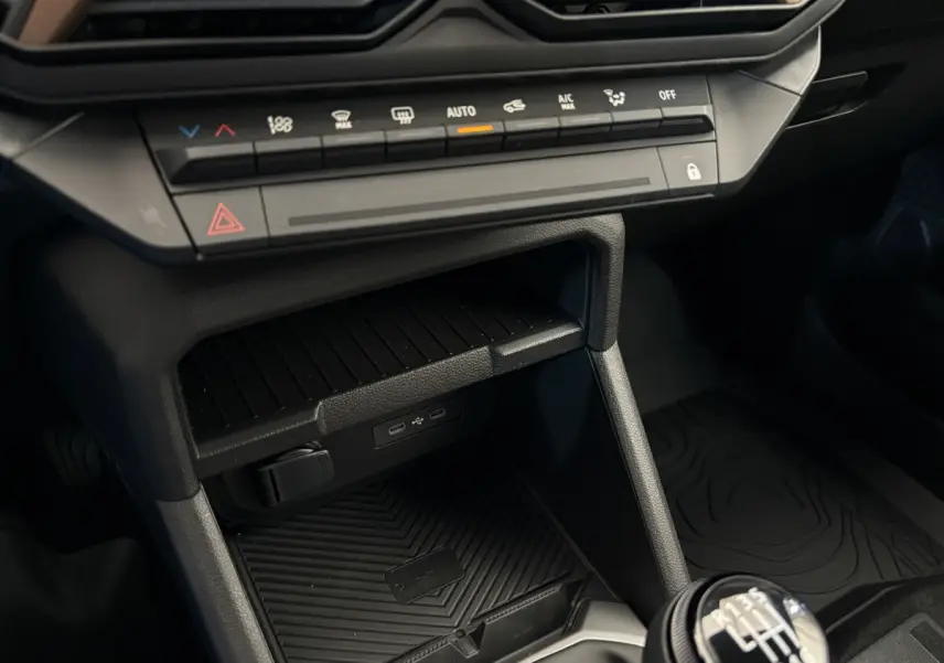 Gros plan sur la console centrale du Dacia Duster noir 2025, montrant la boîte manuelle et les commandes climatisation.