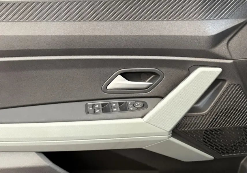 Détail de la porte intérieure côté conducteur du Dacia Duster noir 2025 avec commandes de vitres et poignée argentée.