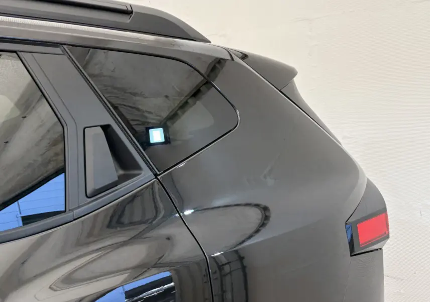 Dacia Duster noir vue en gros plan sur l'arrière droit, mettant en valeur la lunette et le feu arrière.