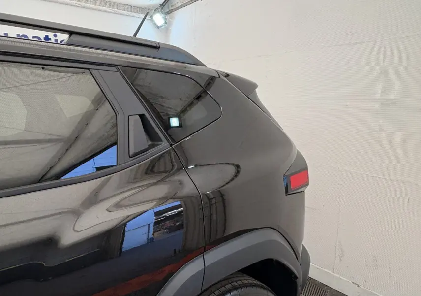 Vue arrière côté gauche du Dacia Duster noir 2025 avec barres de toit et feux arrière LED distinctifs.
