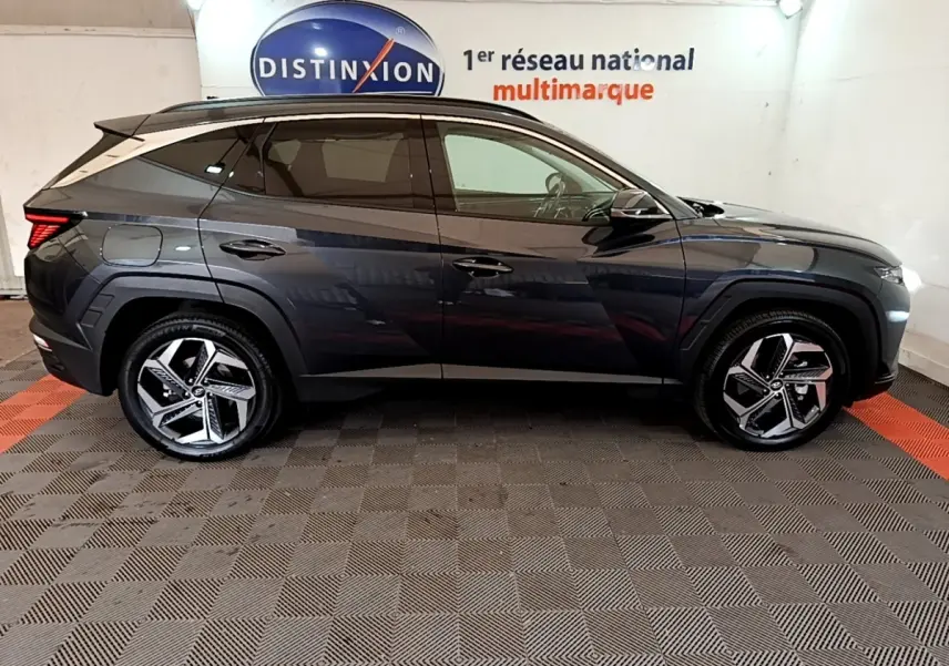 Vue latérale droite d'un Hyundai Tucson gris foncé 2022 avec jantes alliage et toit noir dans un showroom.