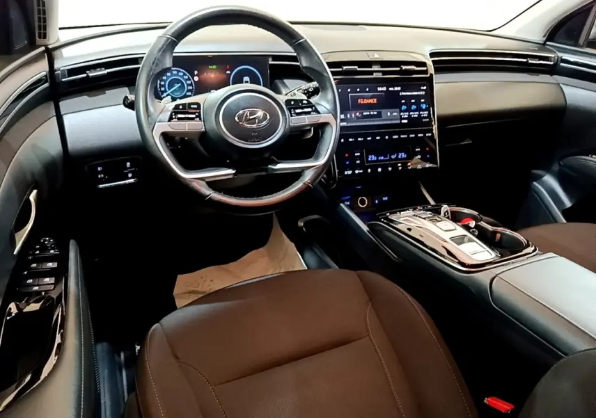 Vue intérieure avant du Hyundai Tucson 2022, tableau de bord noir avec écran tactile central et volant multifonction.