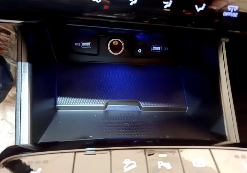 Gros plan sur la console centrale du Hyundai Tucson 2022, montrant les ports USB, prise 12V et recharge sans fil.