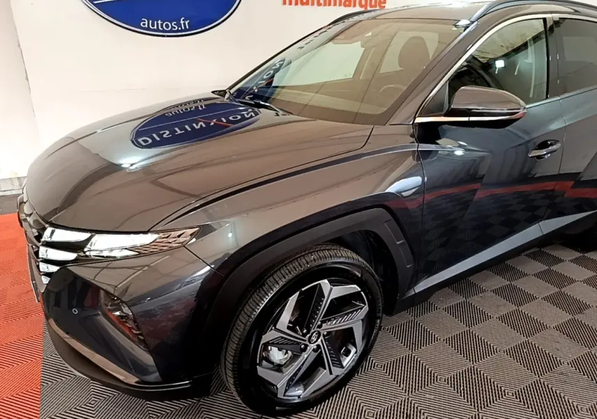 Vue 3/4 avant droit d'un Hyundai Tucson gris foncé avec jantes alliage au design moderne dans un showroom.