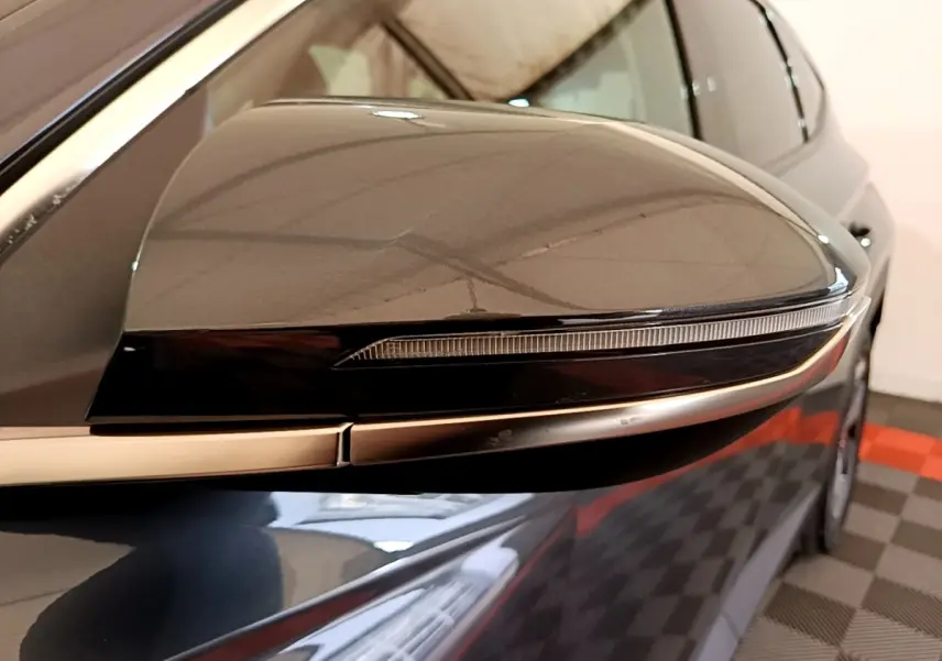 Rétroviseur droit gris foncé du Hyundai Tucson 2022, avec clignotant intégré et carrosserie visible en arrière-plan.