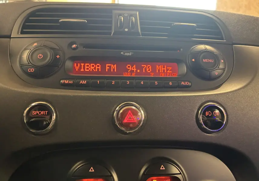 Vue rapprochée du tableau de bord de l'Abarth 500 Competizione 2016, avec radio allumée et boutons rouges SPORT et warning.