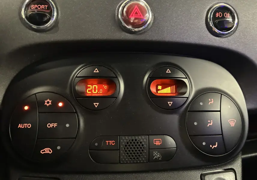 Vue rapprochée du tableau de bord de l'Abarth 500 Competizione 2016, avec commandes de climatisation et bouton sport rouge et gris.