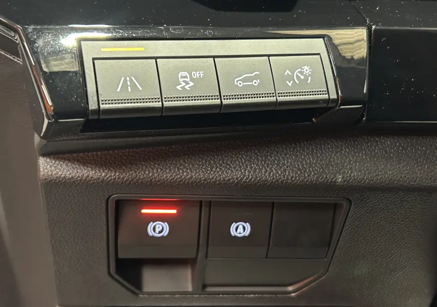 Gros plan sur les boutons de commande du tableau de bord du Renault Austral blanc nacré, avec témoin rouge allumé.