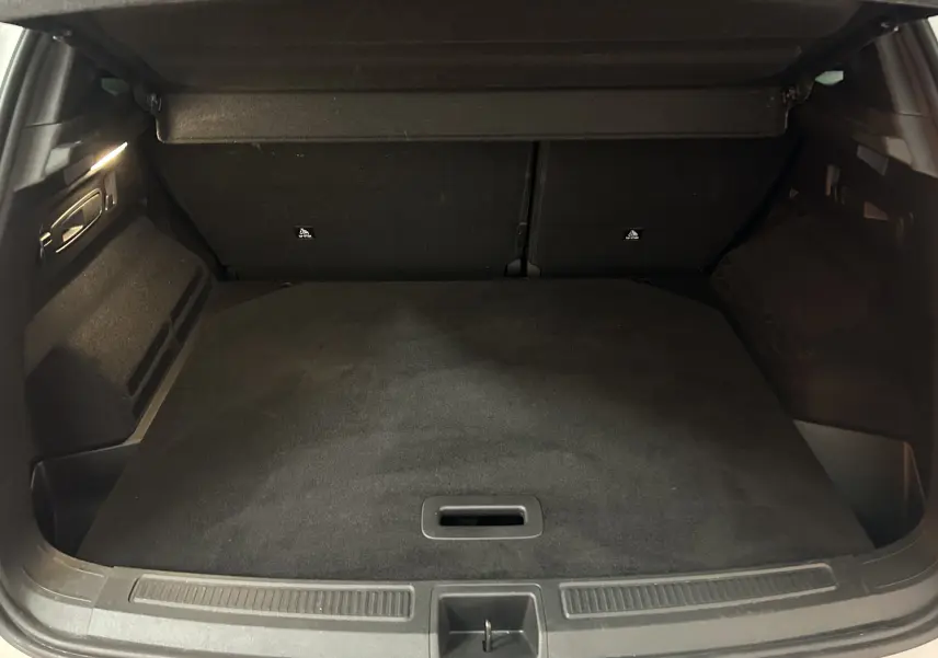 Coffre ouvert vu de l'arrière d'un Renault Austral blanc nacré, espace de chargement propre et vide avec hayon électrique.