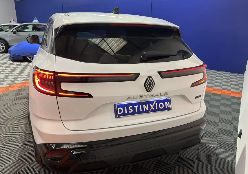Vue arrière d'un Renault Austral blanc nacré avec feux LED allumés dans un showroom intérieur.