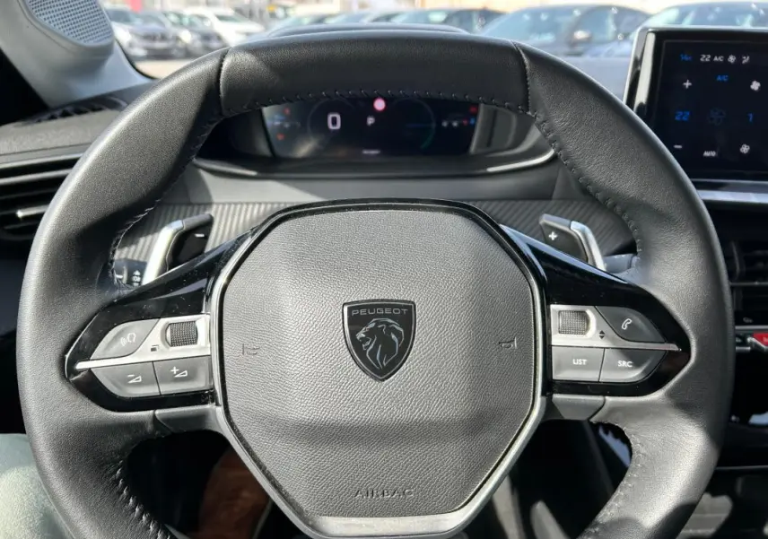 Vue rapprochée du volant cuir noir de la Peugeot 208 Hybrid 110 e-DCS6 Allure 2024 gris, avec commandes intégrées.