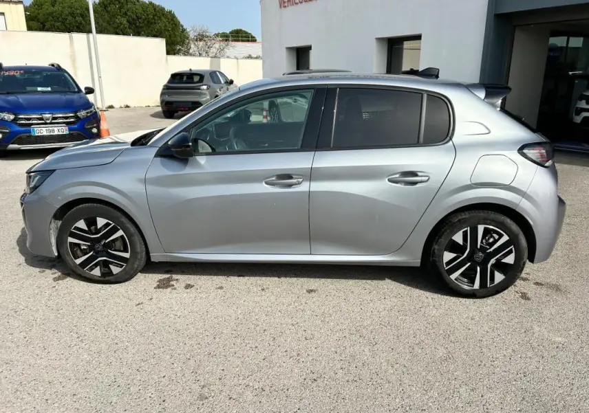 Profil côté gauche d'une Peugeot 208 gris métallisé 2024, avec jantes noires et détails modernes sur les portes.