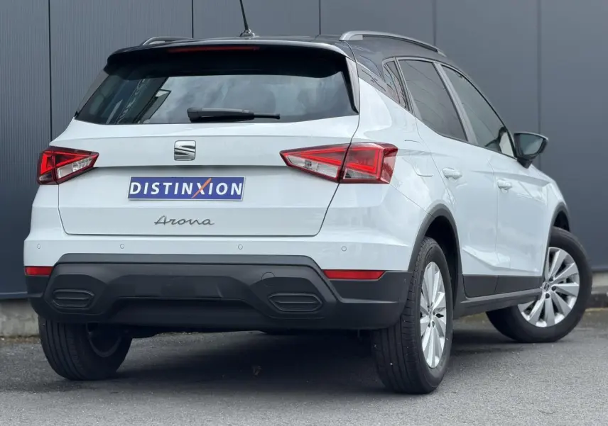 Vue 3/4 arrière droite d'un SEAT Arona blanc alpin avec toit noir et jantes alliage 16 pouces.