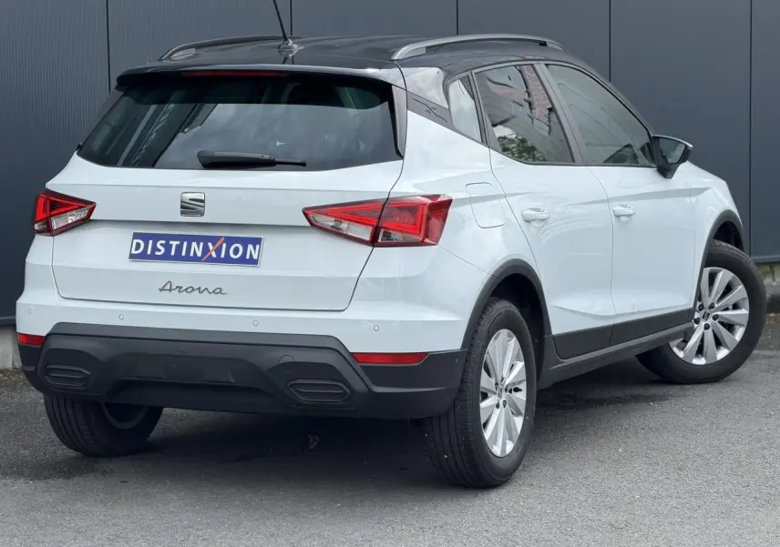 Vue 3/4 arrière droite d'un SEAT Arona blanc alpin avec toit noir et jantes alliage 16 pouces.