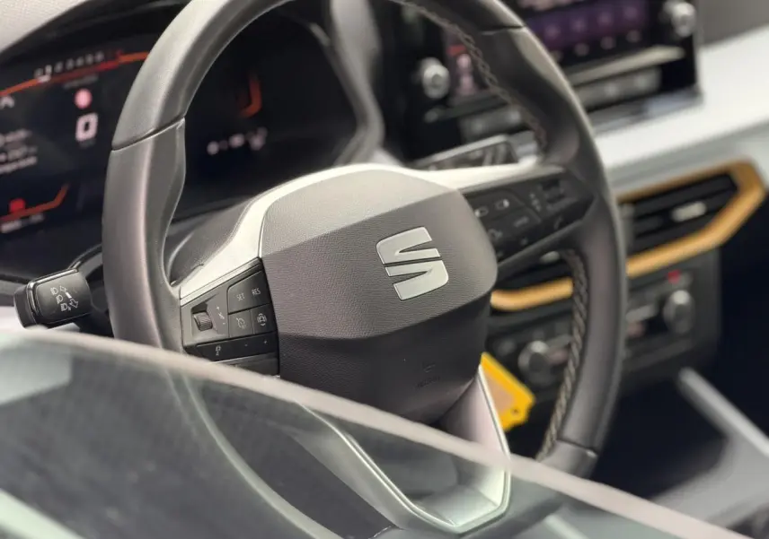 Vue rapprochée du volant noir avec logo SEAT et tableau de bord digital du SUV SEAT Arona 2025.