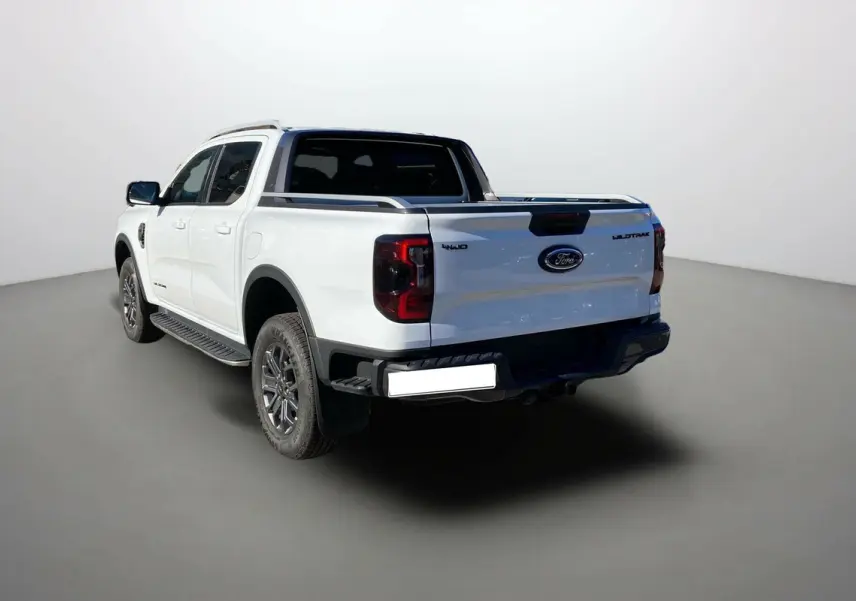 Ford Ranger 2025 blanc glacier en 3/4 arrière droit, avec logo Wildtrak et feux arrière foncés visibles