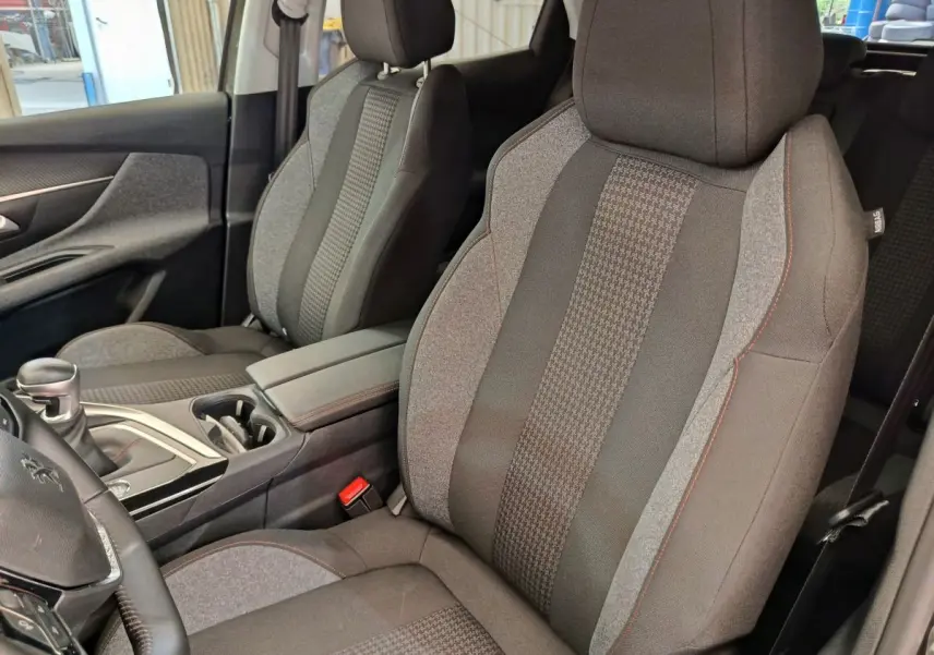 Vue rapprochée des sièges avant en tissu gris du Peugeot 3008 Puretech 130 S&S Active Business 2020, avec console centrale.