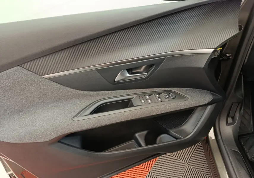 Intérieur côté gauche de la porte avant d’un Peugeot 3008 gris foncé, avec commandes électriques et finition tissu.