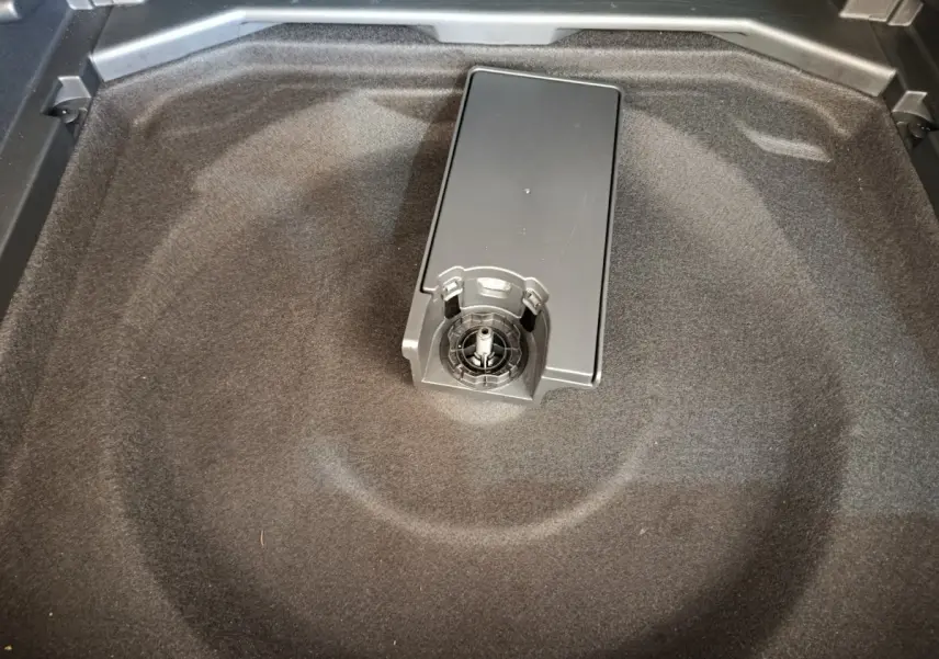 Gros plan sur le rangement sous tablette du coffre du Peugeot 3008 gris foncé, montrant un support central.