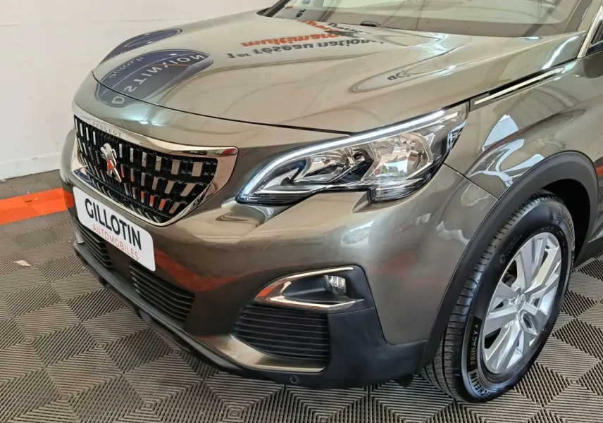 Vue 3/4 avant droit d'un Peugeot 3008 gris foncé avec calandre chromée et feux LED distinctifs.