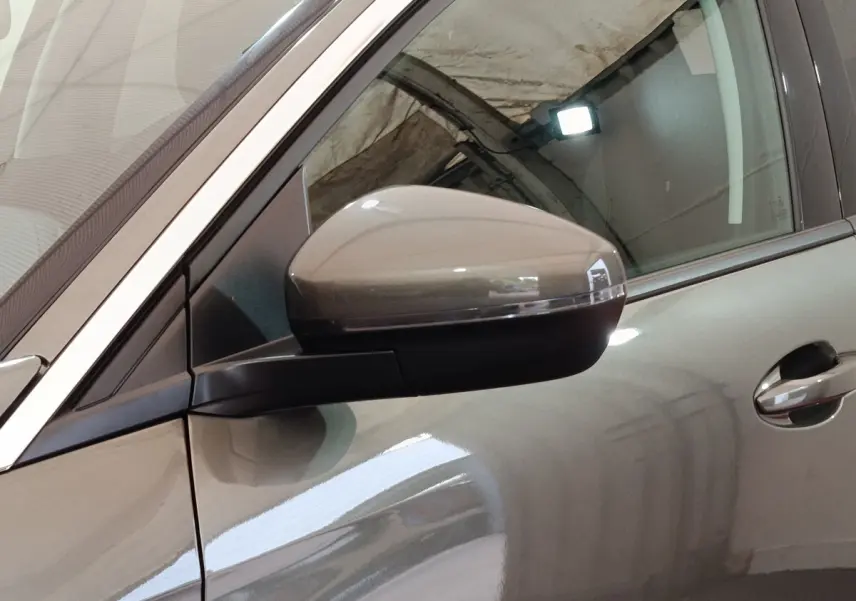 Gros plan sur le rétroviseur côté gauche d'un Peugeot 3008 gris foncé, avec reflet de lumière intérieure.