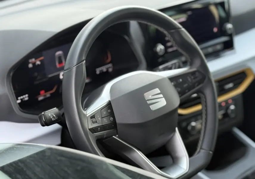 Vue rapprochée du volant noir et du tableau de bord digital du SEAT Arona TSI 115 Style 2025 avec détails modernes.