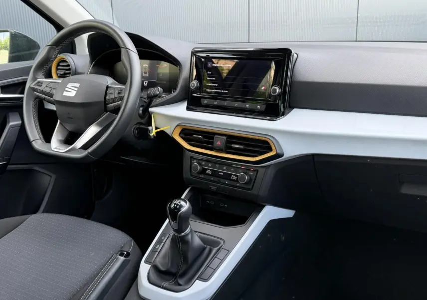 Vue intérieure côté conducteur du tableau de bord du SEAT Arona TSI 115 Style 2025 avec écran tactile et détails jaunes.