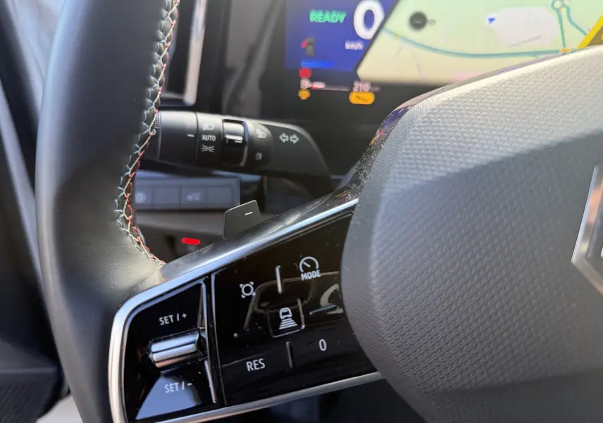 Gros plan sur le volant du Renault Austral Hybrid 2025, montrant les commandes de régulateur et l'écran digital en arrière-plan.