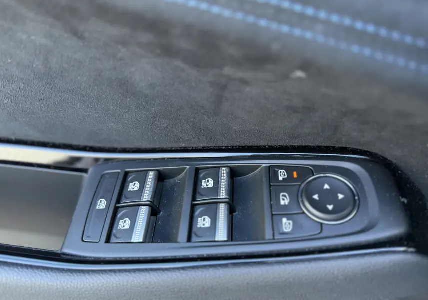 Gros plan sur les commandes des vitres et rétroviseurs côté conducteur d’un Renault Austral blanc nacré, finition Alpine.