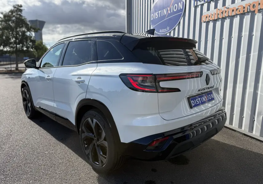 Vue 3/4 arrière droite du Renault Austral blanc nacré avec toit noir, feux LED et jantes noires distinctives.