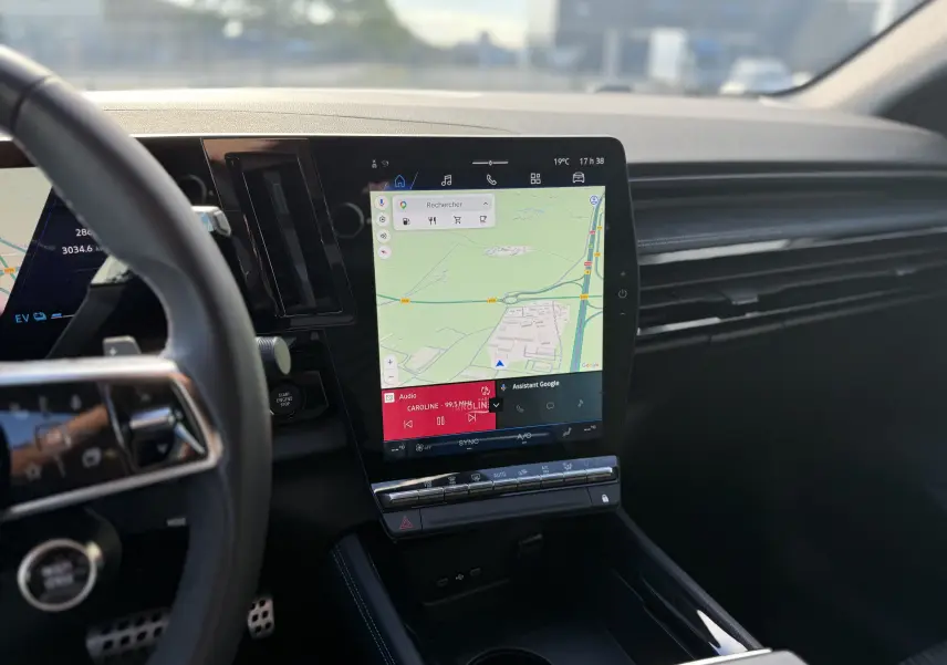 Vue intérieure centrée sur l'écran tactile vertical du tableau de bord du Renault Austral Hybrid 2025, avec volant partiel visible.
