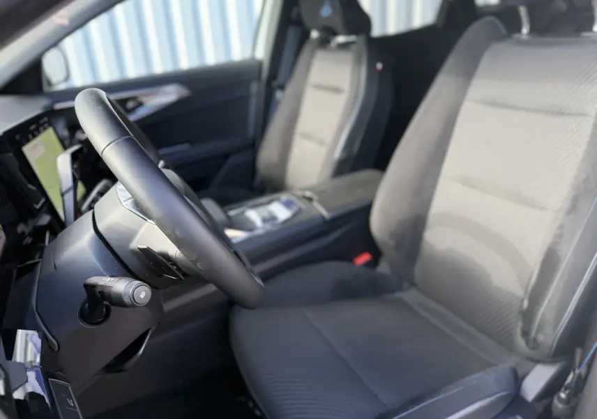 Vue intérieure côté conducteur du Renault Austral Hybrid 2025, sièges en tissu et cuir noir avec volant multifonction.