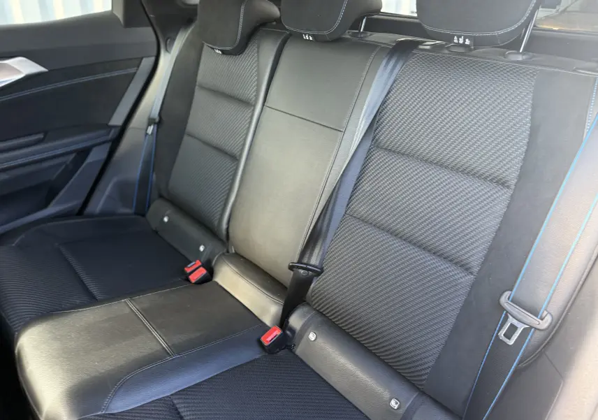 Vue rapprochée des sièges arrière noirs en cuir et tissu avec surpiqûres bleues du Renault Austral Hybrid 2025.
