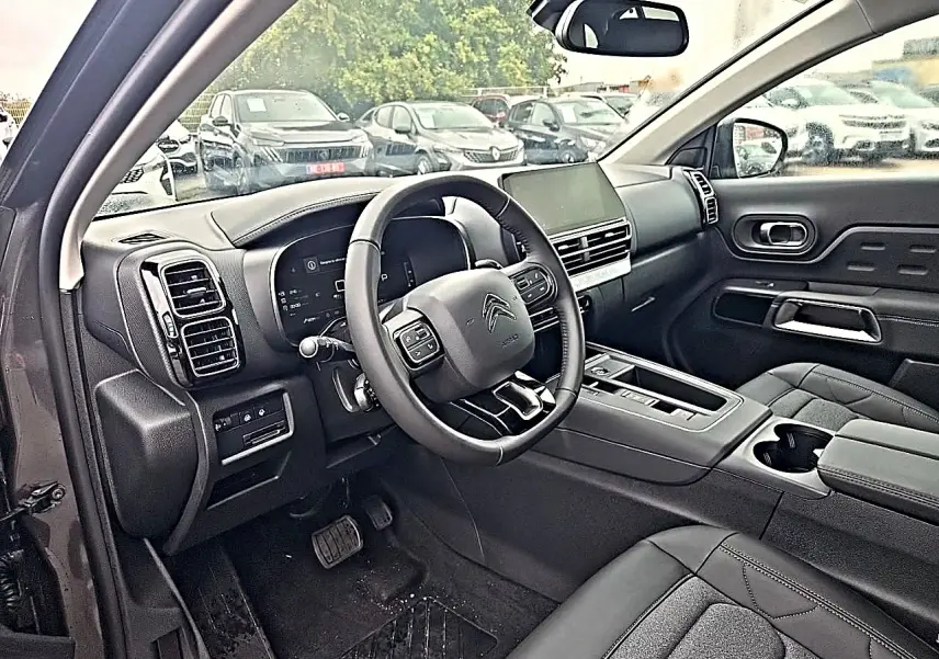 Vue intérieure côté conducteur du Citroën C5 Aircross gris, volant cuir multifonction et écran tactile central visible.