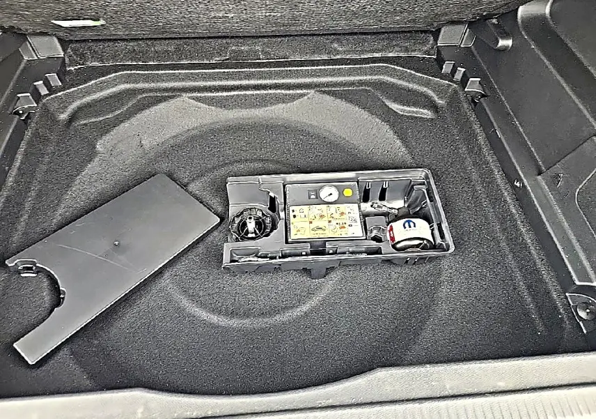 Vue plongeante sur le coffre gris du Citroën C5 Aircross 2025, montrant le rangement sous plancher avec kit de réparation.