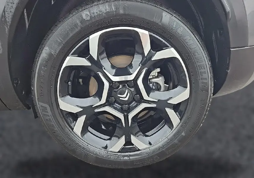 Gros plan sur la jante alu bicolore noire et argent du Citroën C5 Aircross gris, mettant en valeur le logo Citroën central.