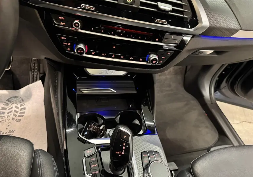 Vue intérieure centrée sur la console centrale noire brillante du BMW X4 Carbonschwarz 2020 avec levier de vitesse automatique.