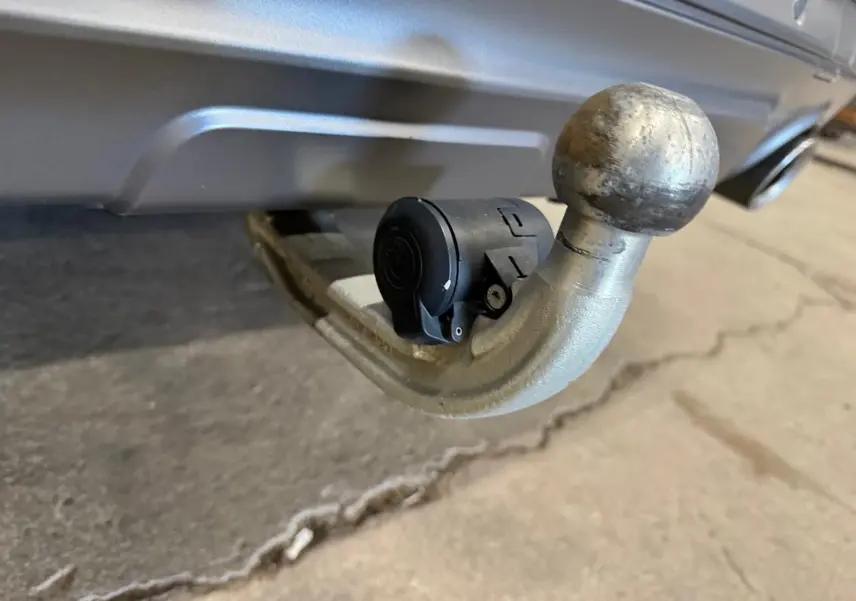 Gros plan sur l'attelage d'une BMW X4 Carbonschwarz 2020, mettant en valeur la boule d'attelage métallique et la prise électrique noire.